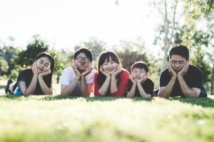 Family lying together on a lawn resting chins on hands